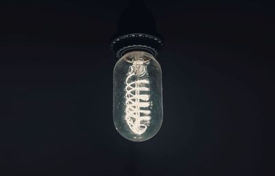 Low angle view of illuminated light bulb against black background