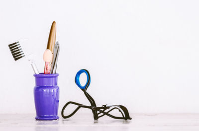 Close-up of make-up tools on table against white background