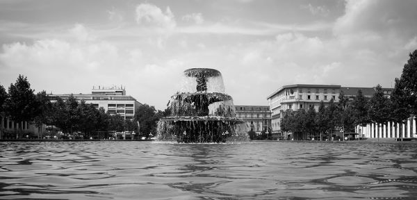 Surface level of fountain in city against sky