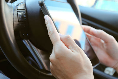 Cropped hand of person using mobile phone in car