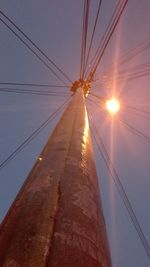 Low angle view of electricity pylon against sky during sunset