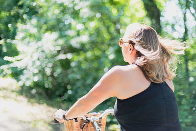 Side view of woman standing against tree