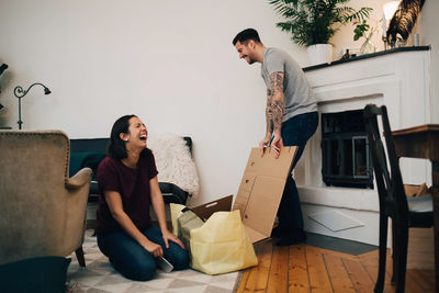 Cheerful couple unpacking boxes in living room at new home