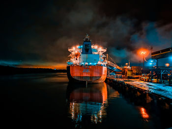 Ship moored on sea against sky at night