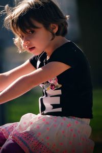 Cute girl looking away while sitting in playground