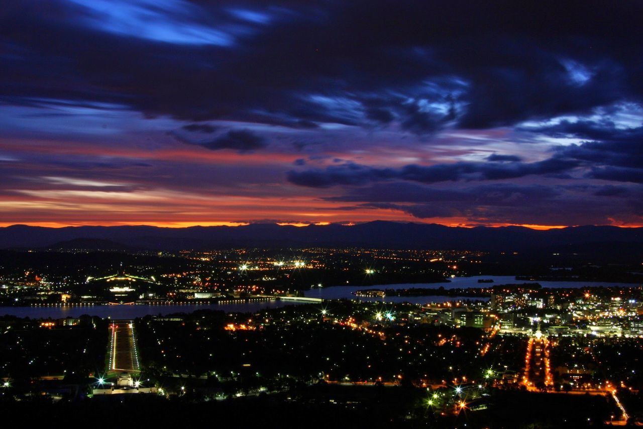 HIGH ANGLE VIEW OF ILLUMINATED CITY BUILDINGS AT NIGHT