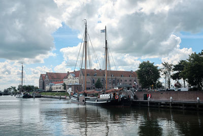 Sailboats in river by city against sky