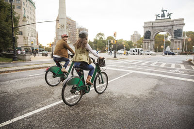 Couple riding bicycle on city street