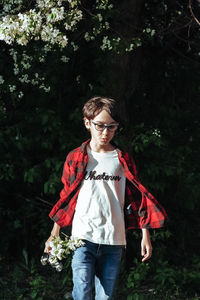 Full length of young woman standing by tree in forest