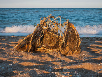 Old used dirty fishing nets rusty wire, garbage dumped on sea beach sand. environmental pollution.