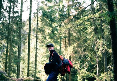 Side view of backpacker standing in forest