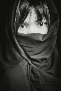 Close-up portrait of young woman wrapped in scarf