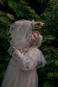 Young woman with white standing against plants