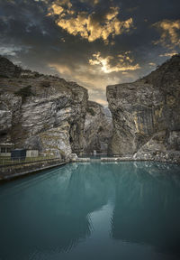 Reflection of rocks in swimming pool against sky