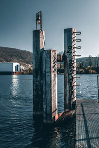 Wooden posts in sea against sky