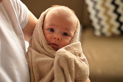 Newborn baby girl in towel after bath held by her mother
