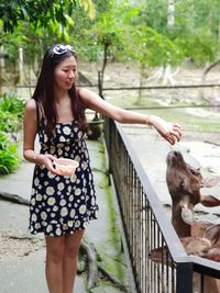 Young woman smiling while standing against railing