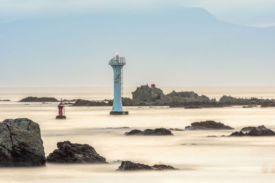 Lighthouse by sea against sky