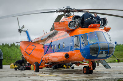 Soldiers and helicopter on runway against sky