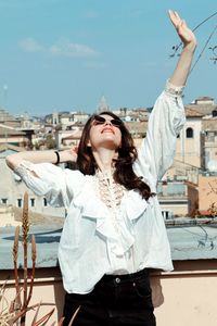 Portrait of young woman standing against sky