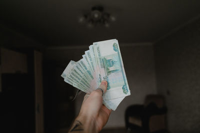 A man's hand holds the starting currency, shows how much he earned, remote work is profitable