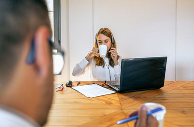 Woman with headset in customer help service taking a break and drinking cup of coffee