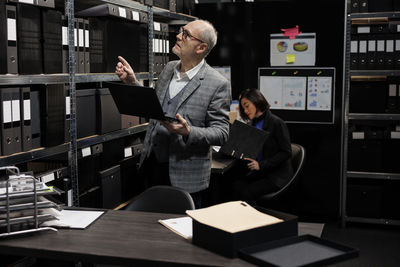 Portrait of young businesswoman using digital tablet while standing in office