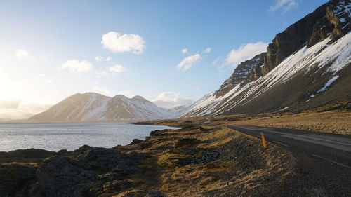 Scenic view of snowcapped mountains by sea against sky
