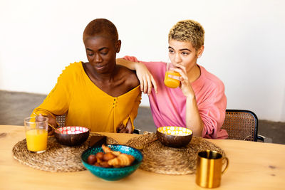 Lesbian couple having breakfast on table at home