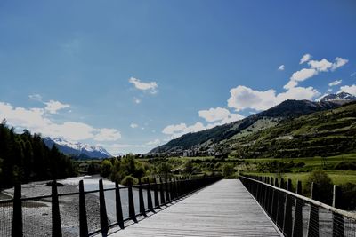 Footbridge over lake against sky