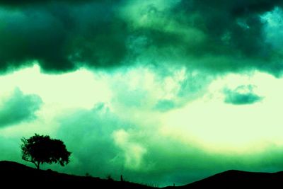 Low angle view of storm clouds over silhouette landscape