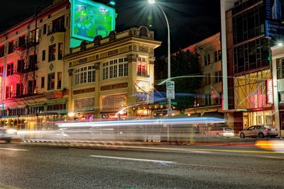 Light trails on city street by buildings at night