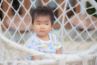 Portrait of cute baby girl looking through fence