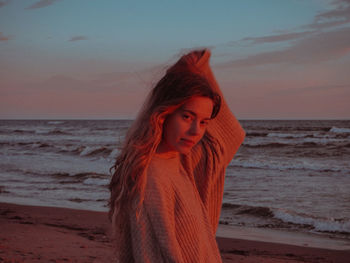 Woman looking at sea against sky during sunset