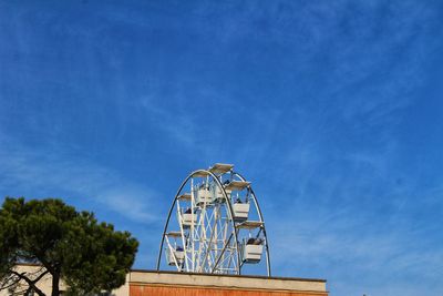 Low angle view of ferris wheel against blue sky