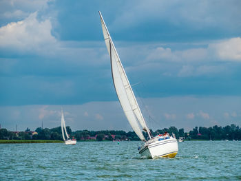 Sailing yacht or sailboat on full sails swims on a lake in a windy day