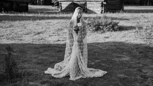 Full length of girl wearing textile and holding flower standing outdoors