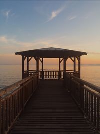 Pier over sea against sky during sunset