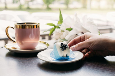 Cropped hand of woman holding coffee on table