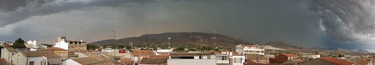 Buildings in town against cloudy sky