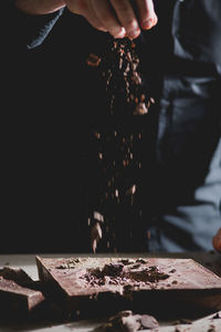 Midsection of man putting chocolate shavings on table
