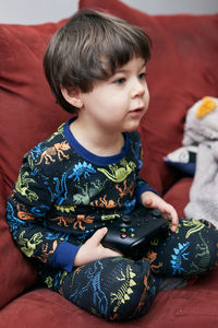 Cute boy with a game pad playing on the couch playing games