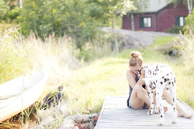 Woman playing with dalmatian dog at jetty