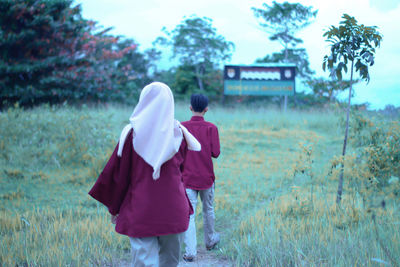 Rear view of couple walking on field