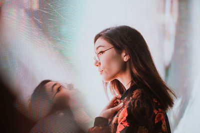 Close-up of young woman standing against illuminated city at night