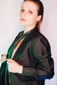 Portrait of young woman standing against white background wearing a tie 