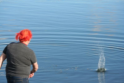 Woman throwing pebble in blue water