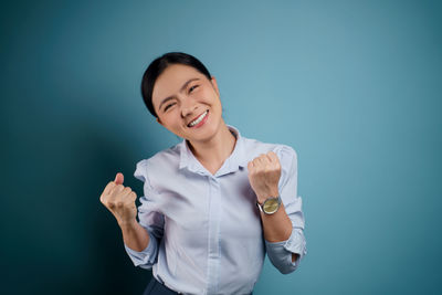 Portrait of a smiling young woman against blue background