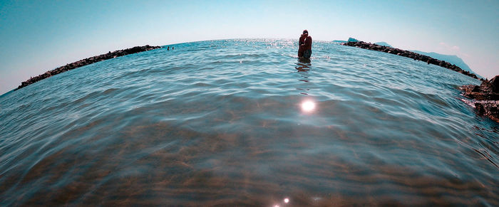 Person on sea against clear blue sky