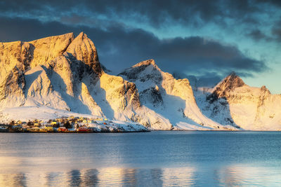 Scenic view of sea and snowcapped mountains against sky